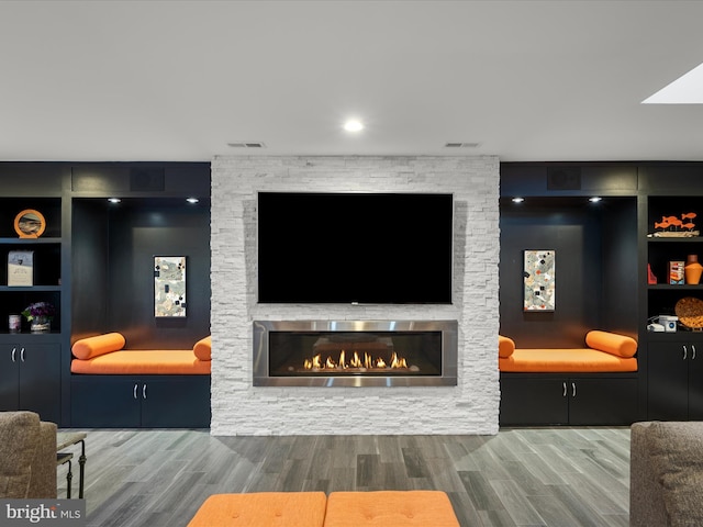 living room featuring wood finished floors, a fireplace, and visible vents