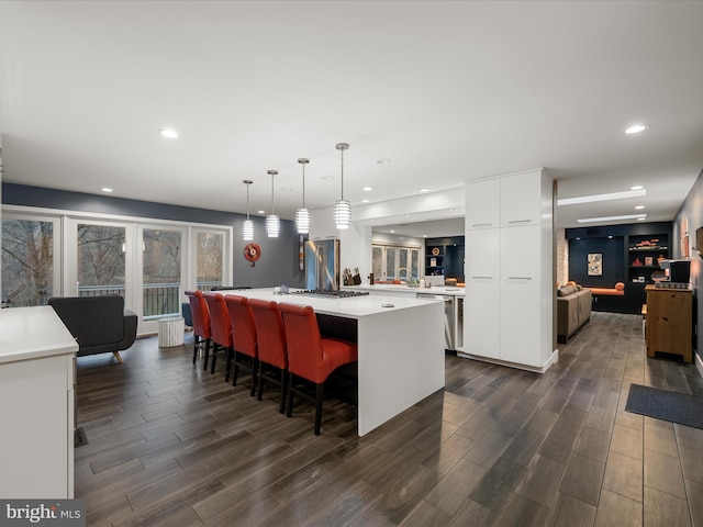 kitchen featuring wood finish floors, modern cabinets, white cabinetry, light countertops, and hanging light fixtures