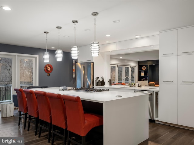 kitchen featuring a kitchen island, dark wood-style flooring, white cabinets, appliances with stainless steel finishes, and modern cabinets