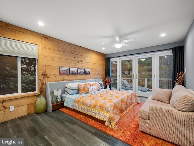 bedroom with dark wood finished floors, recessed lighting, french doors, wood walls, and access to outside