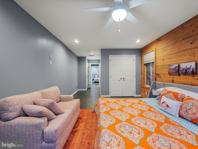 bedroom with baseboards, wood walls, recessed lighting, wood finished floors, and a closet