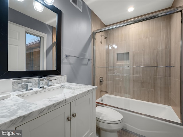 bathroom featuring visible vents, combined bath / shower with glass door, toilet, and vanity