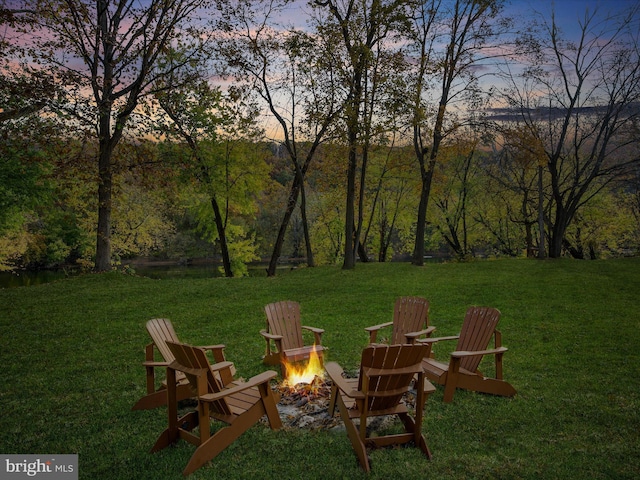 view of yard with a view of trees and an outdoor fire pit