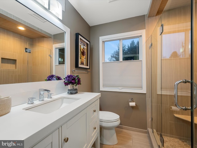 bathroom with vanity, toilet, baseboards, and a stall shower