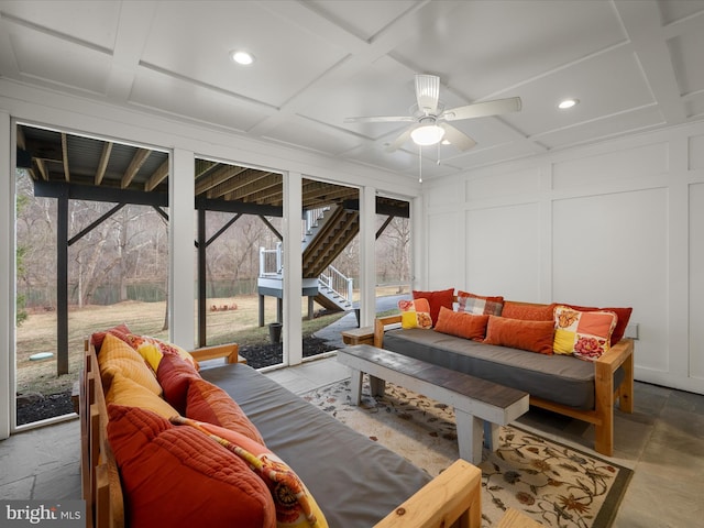 living room with a decorative wall, coffered ceiling, and a sunroom