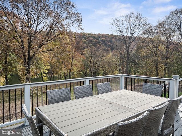 wooden deck featuring outdoor dining space and a wooded view