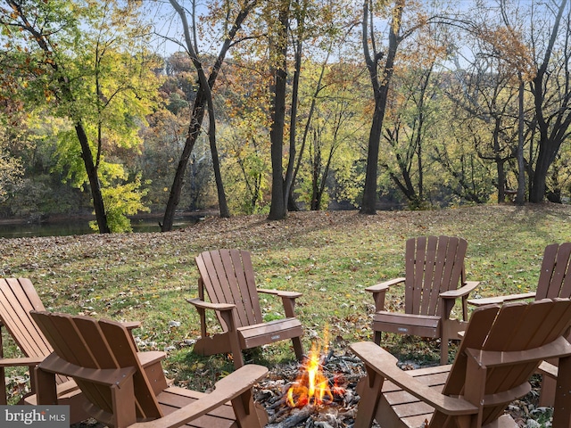 view of yard featuring a fire pit and a view of trees