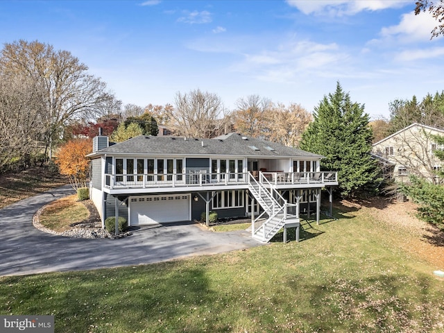 back of house featuring an attached garage, a wooden deck, stairs, a lawn, and driveway