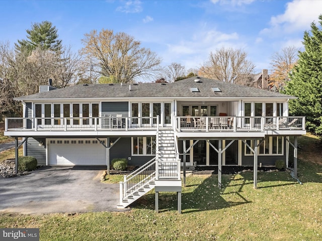 back of property featuring stairway, a yard, a chimney, a garage, and aphalt driveway