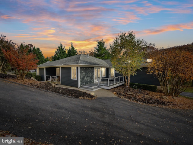 ranch-style house featuring roof with shingles and covered porch