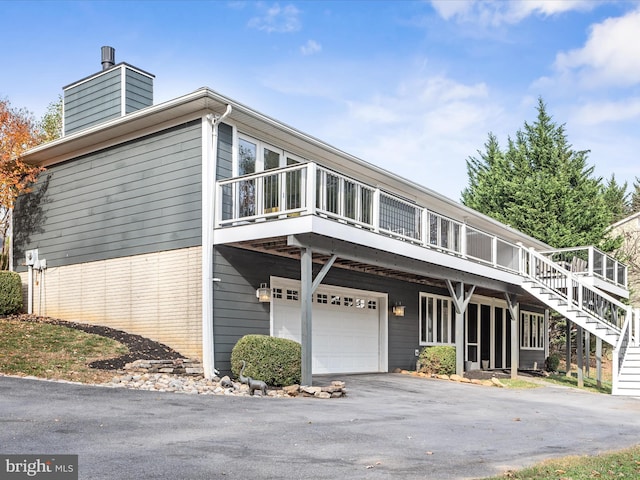 view of front of property with aphalt driveway, stairway, an attached garage, and a chimney