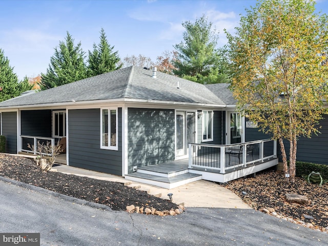 ranch-style house featuring a deck and roof with shingles