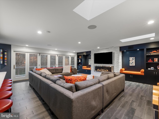 living area with a fireplace, a skylight, built in shelves, and wood tiled floor