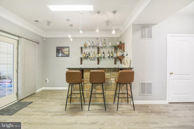 bar featuring visible vents, crown molding, a bar, and wood finished floors