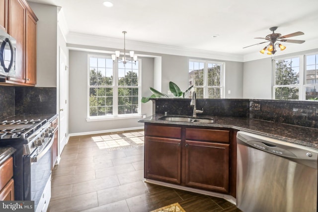 kitchen featuring crown molding, decorative backsplash, appliances with stainless steel finishes, a sink, and dark stone countertops