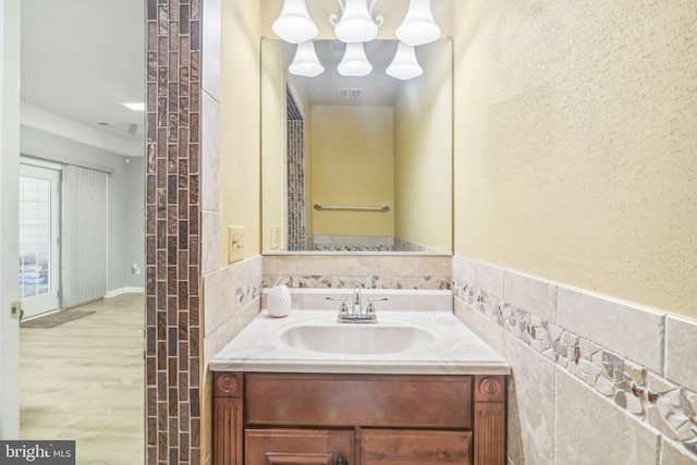 bathroom featuring wood finished floors, vanity, visible vents, and tile walls