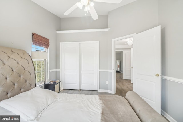 bedroom featuring ceiling fan, a closet, baseboards, and wood finished floors