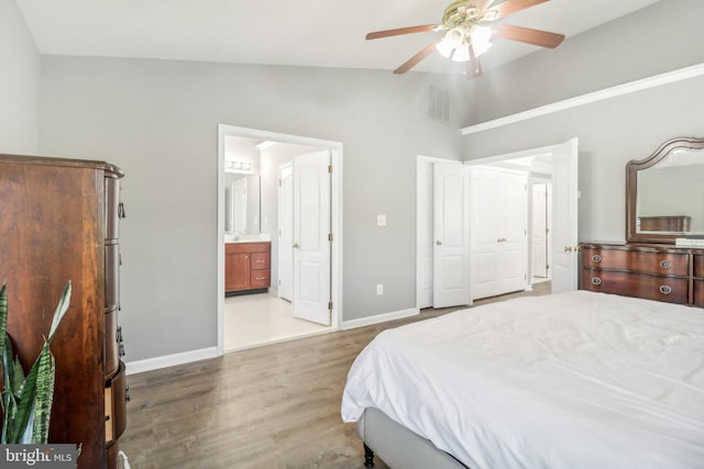 bedroom with connected bathroom, wood finished floors, visible vents, baseboards, and vaulted ceiling