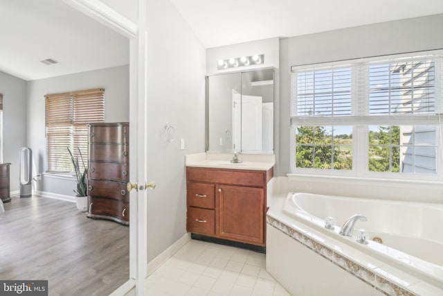 full bathroom featuring baseboards, visible vents, a bath, and vanity