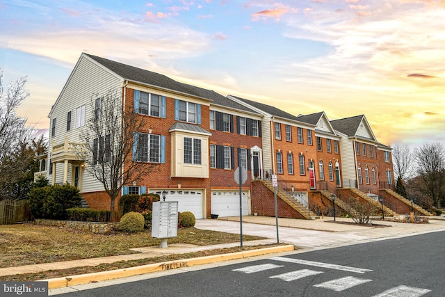 townhome / multi-family property with driveway, a garage, a residential view, central AC, and brick siding