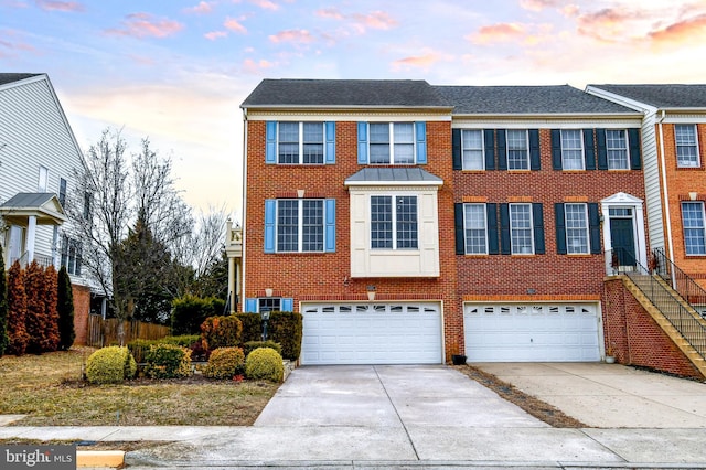 townhome / multi-family property with a garage, brick siding, and driveway