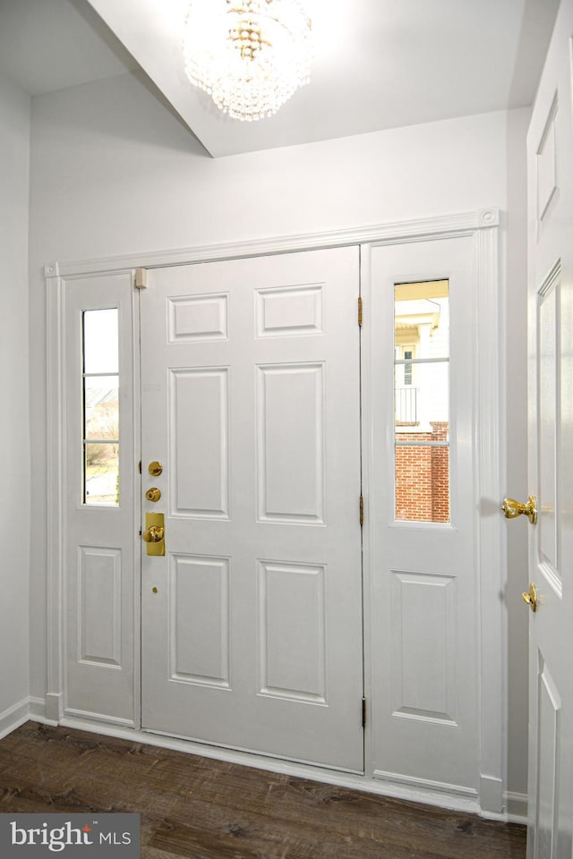 entrance foyer featuring dark wood-type flooring, baseboards, and an inviting chandelier