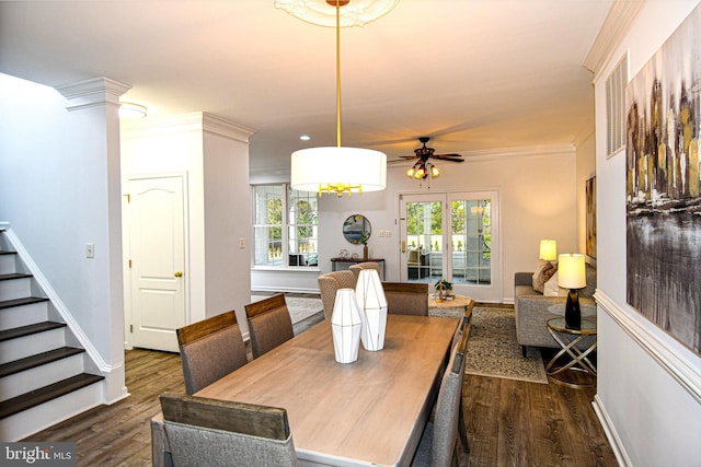 dining room featuring dark wood-style flooring, crown molding, decorative columns, and stairs