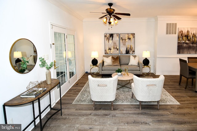 living area with ceiling fan, wood finished floors, visible vents, and crown molding