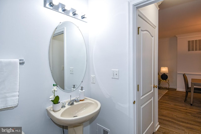 bathroom with ornamental molding, visible vents, a sink, and wood finished floors