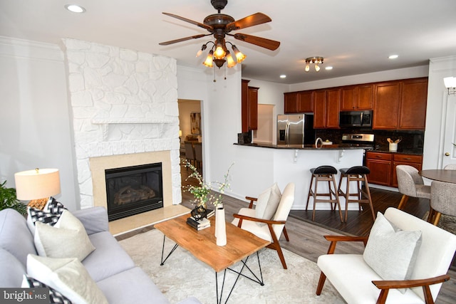 living area featuring dark wood-style flooring, crown molding, a fireplace, recessed lighting, and ceiling fan