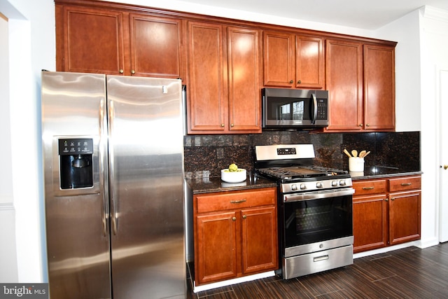 kitchen featuring appliances with stainless steel finishes, dark stone countertops, brown cabinets, and tasteful backsplash