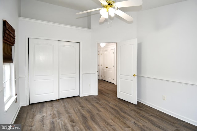 unfurnished bedroom with dark wood-style floors, ceiling fan, a closet, and baseboards