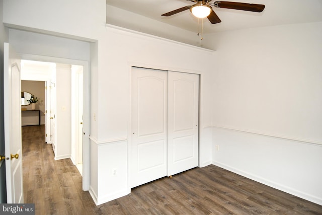 unfurnished bedroom with ceiling fan, a closet, baseboards, and dark wood-style flooring