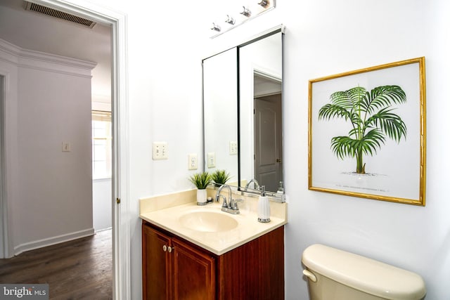 bathroom with toilet, wood finished floors, vanity, and visible vents