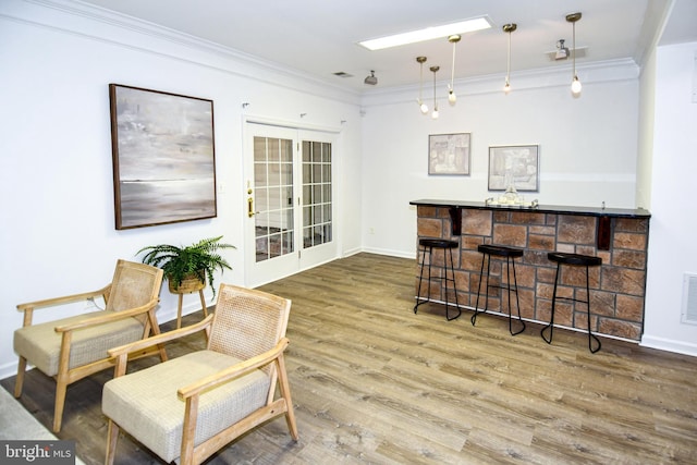 bar with a dry bar, baseboards, visible vents, ornamental molding, and wood finished floors