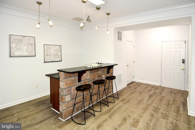 bar with baseboards, visible vents, wood finished floors, crown molding, and a bar