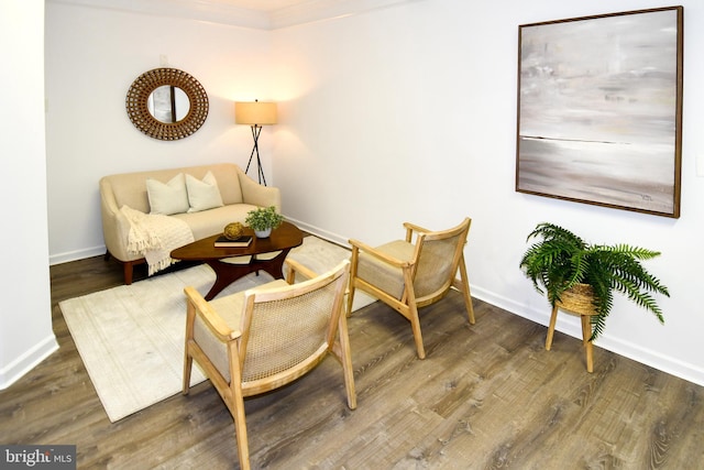 sitting room featuring crown molding, baseboards, and wood finished floors