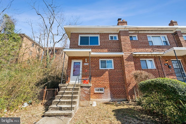 view of front of home with brick siding and a chimney