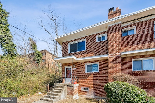 view of front of house with a chimney and brick siding