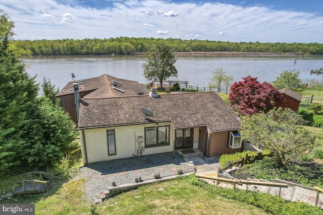 view of front of home featuring a forest view, a water view, and roof with shingles