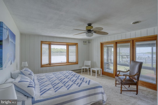 carpeted bedroom with a ceiling fan, visible vents, a baseboard radiator, a textured ceiling, and access to outside