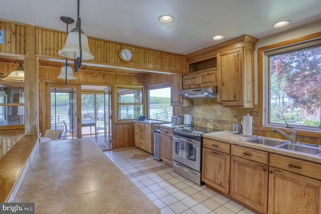 kitchen with a sink, light countertops, stainless steel range with electric stovetop, under cabinet range hood, and backsplash