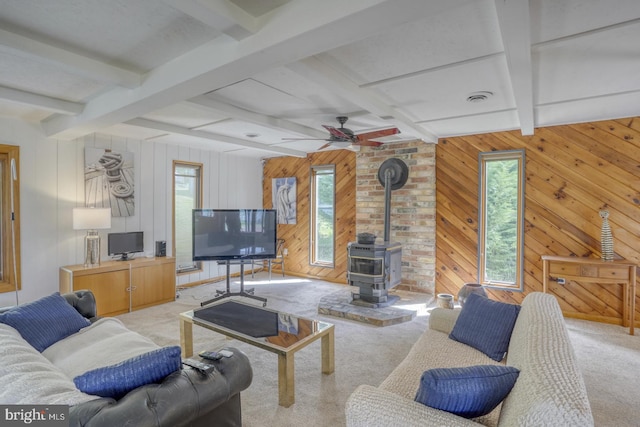 living area with visible vents, beam ceiling, a ceiling fan, carpet flooring, and a wood stove