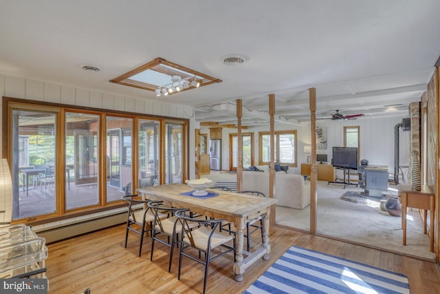 dining area with light wood finished floors, visible vents, and baseboard heating