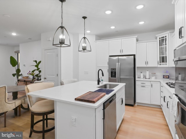 kitchen with decorative light fixtures, stainless steel appliances, a kitchen island with sink, a sink, and a kitchen breakfast bar