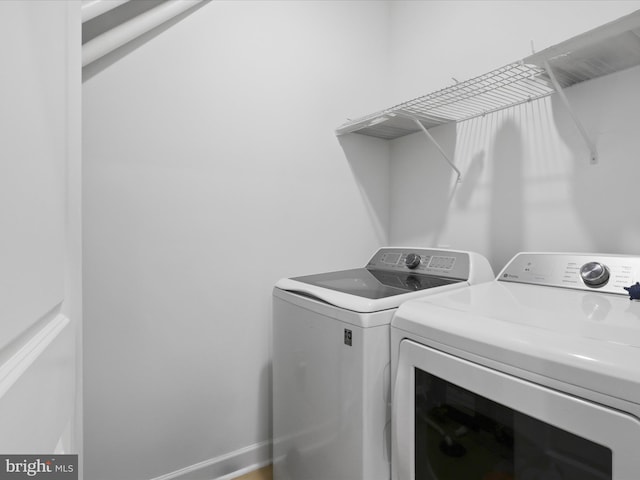 washroom featuring laundry area, separate washer and dryer, and baseboards