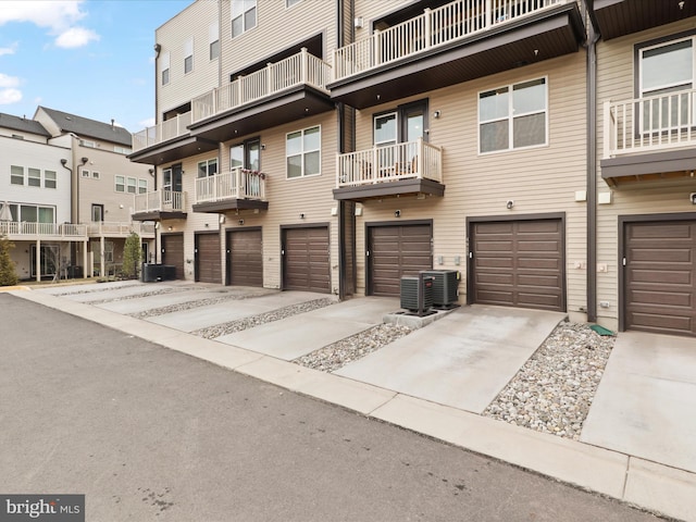 view of front of home with a garage, concrete driveway, and central AC unit