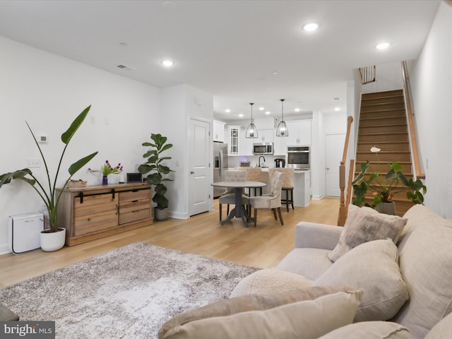 living area with stairway, light wood-type flooring, visible vents, and recessed lighting