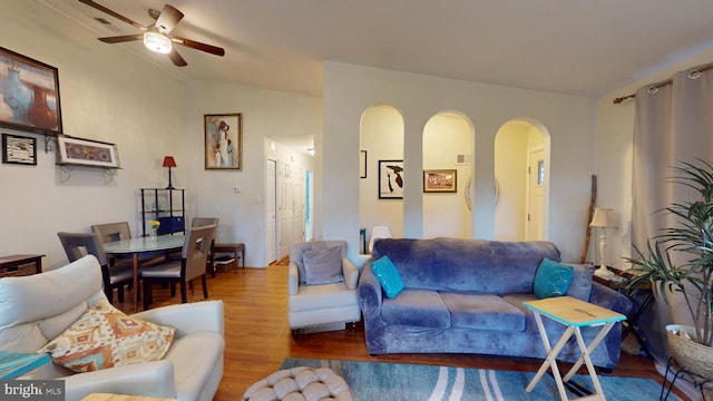 living area featuring arched walkways, ceiling fan, vaulted ceiling, and wood finished floors