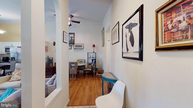 corridor featuring light wood-type flooring and crown molding